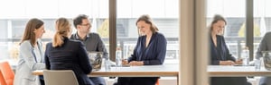 The Metecon team engaged in a professional discussion at a conference table in a modern office.